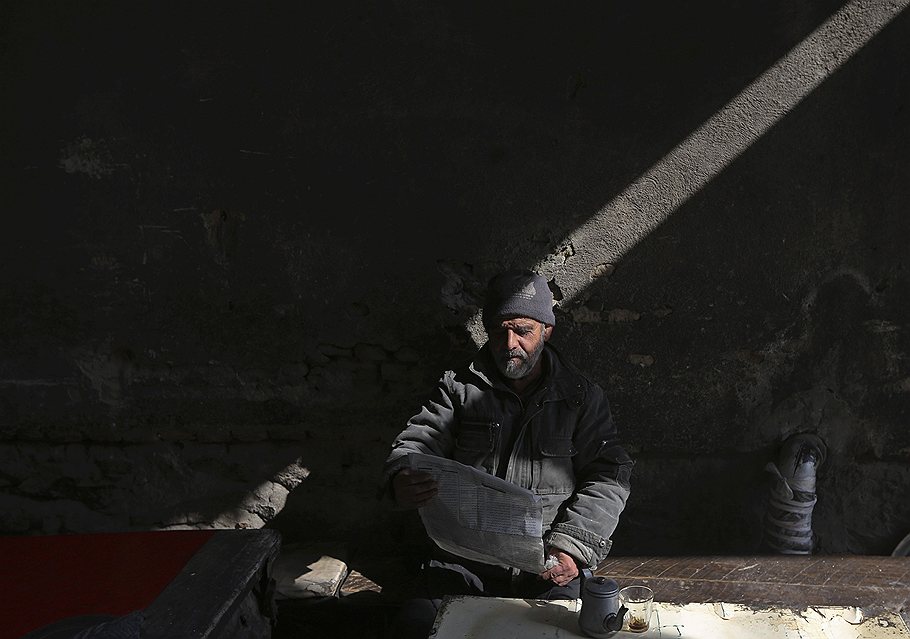 Житель Кабула читает газету в чайной.