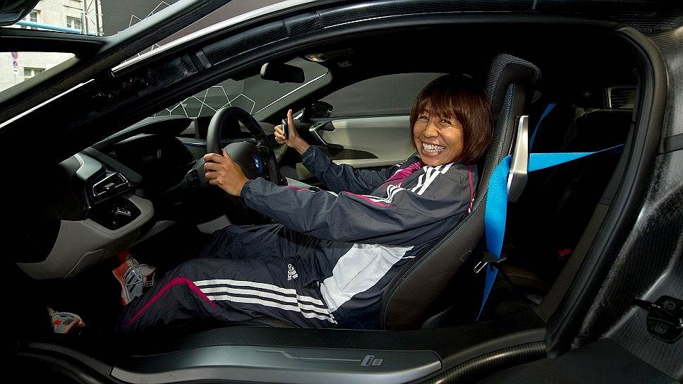 Японская легкоатлетка Фукуси Каёко, бронзовый призер чемпионата мира 2013 года в марафоне и чемпионка Азиатских игр 2006 года на дистанции 10 тыс. метров, позирует фотографам за рулем BMW i8 накануне Берлинского марафона 2014 года