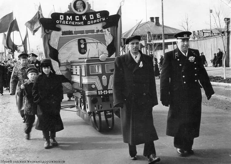 Для демонстрации 7 ноября 1965 года омские железнодорожники выбрали транспортное средство, как сказали бы сегодня, «с нулевым углеродным следом» - велосипед. На него водружен макет не менее дружелюбного к окружающей среде локомотива — электровоза ВЛ-23.