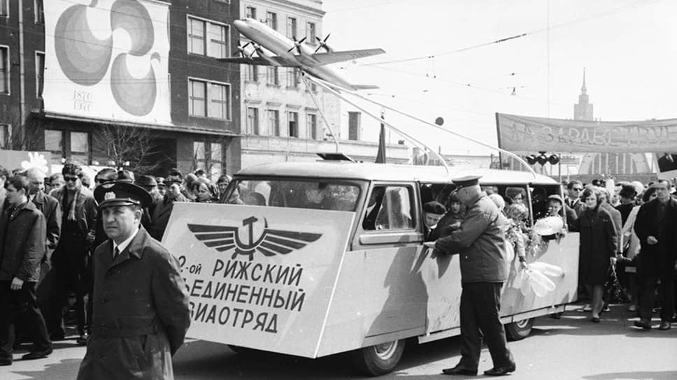 Первомайская демонстрация середины 70-х на Комсомольской набережной в Риге. Микроавтобус RAF-980 местного производства везет на крыше макет самолета Ил-18, выпускавшегося в Москве.