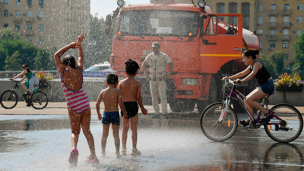 Поливальный автомобиль и дети во время жары в московском Парке Горького