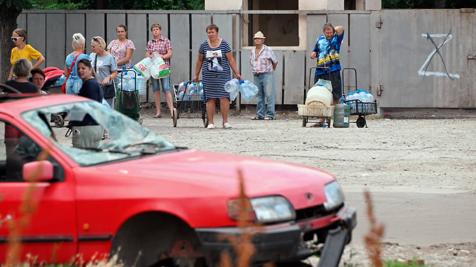 Жители Мариуполя на остановке городского транспорта с бутылками питьевой воды