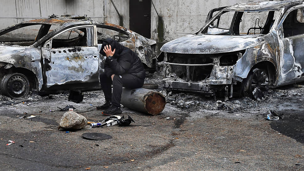 Январь 2022. Последствия волнений  в Казахстане. Мужчина сидит рядом с сожженными автомобилями