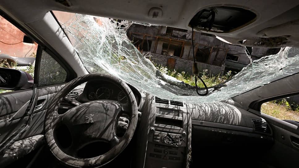 Июль 2022. Разбитый автомобиль во дворе разрушенного многоквартирного дома в Мариуполе 