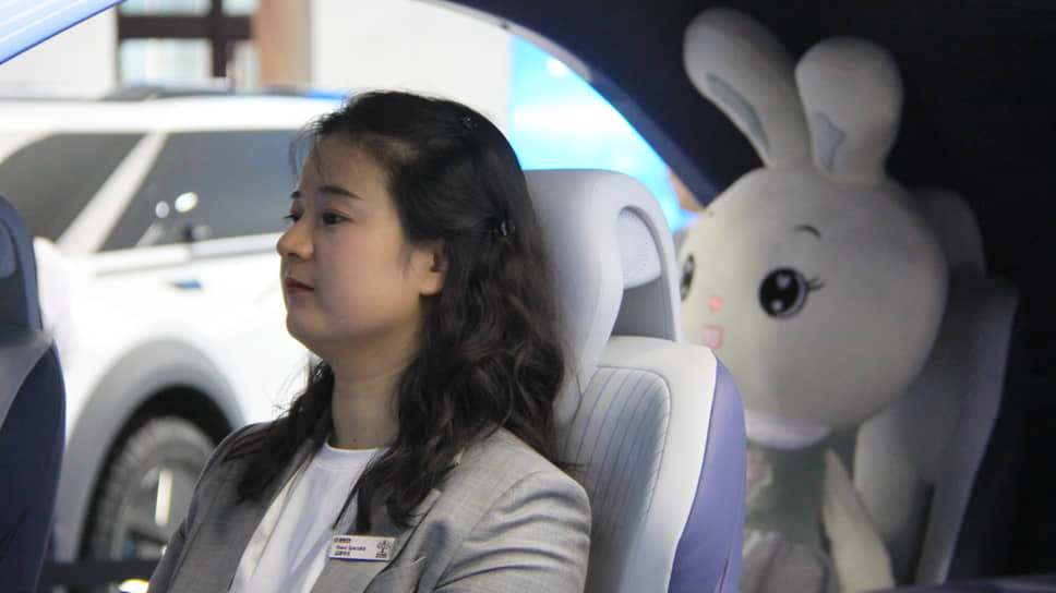 Стендистка отдыхает в инсталляции под названием Smart cockpit на стенде Dongfeng