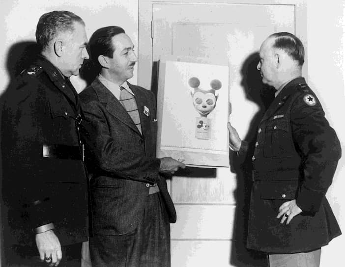 Поклонниками творчества были Гитлер и Сталин. По одной из версий, в 1937 году Геббельс подарил фюреру 12 мультфильмов про Микки Мауса. Но в 1939 году Disney запросил слишком большую сумму за прокат «Белоснежки» в Германии, и Гитлер разлюбил мышонка. К советскому зрителю Микки Маус пришел в 1935 году и так понравился Сталину, что он подписал приказ о создании «Союздетмультфильма»
&lt;br>На фото: Уолт Дисней (второй слева) передает американским военным зарисовку защитной маски, которая, по мысли создателей, предназначалась для использования детьми во время газовой атаки, 1942 год