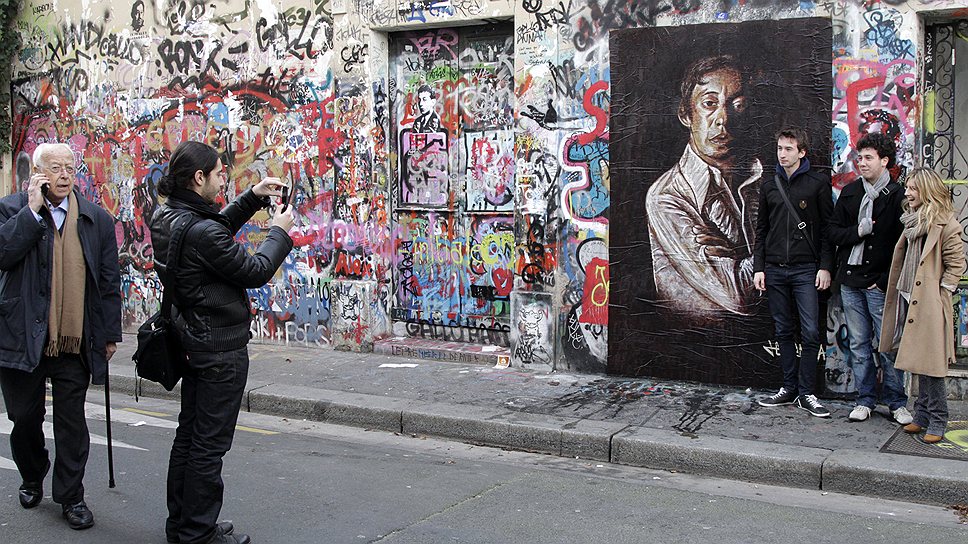 Люди рядом с граффити и картинами Сержа Генсбура на стене дома музыканта на улице Верней в Париже. 2 марта 2011 года -- тогда фанаты праздновали 20-ю годовщину смерти Генсбурга 
