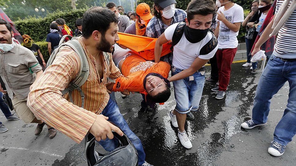 Протестующие несут пострадавшего на митинге в Анкаре