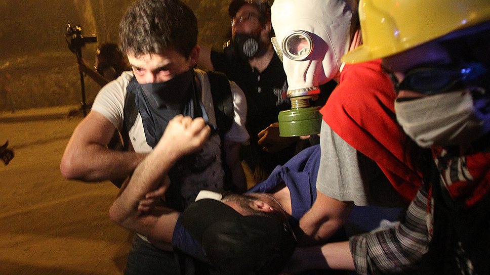 Демонстранты в противогазах помогают пострадавшему во время беспорядков у офиса правящей партии Турции 