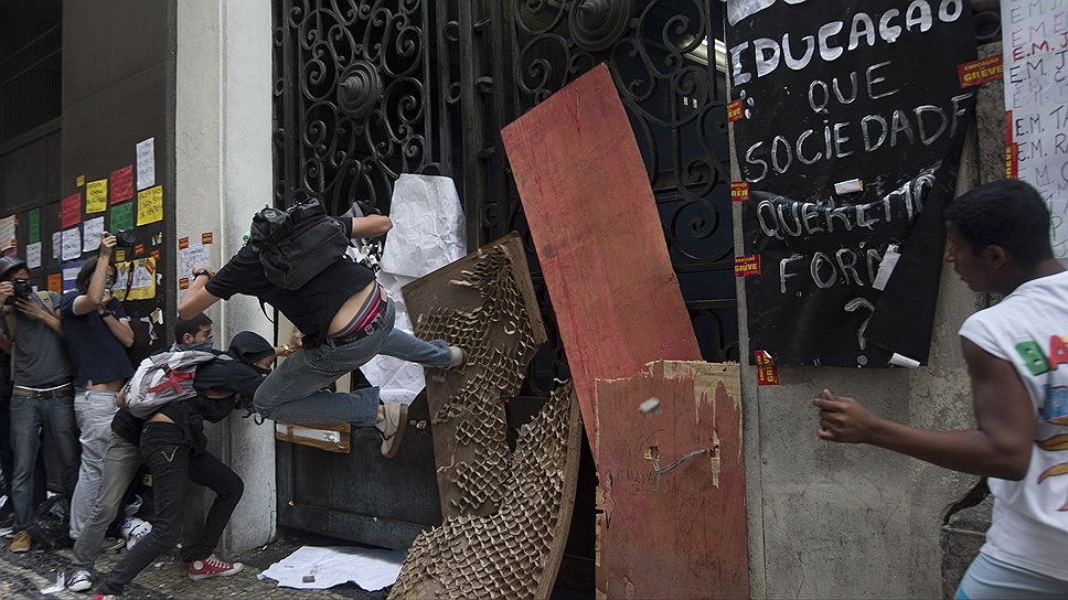 Демонстранты штурмуют здание мэрии Рио-де-Жанейро. Надпись на плакате: «В трауре: Образование, какое общество мы хотим построить?»