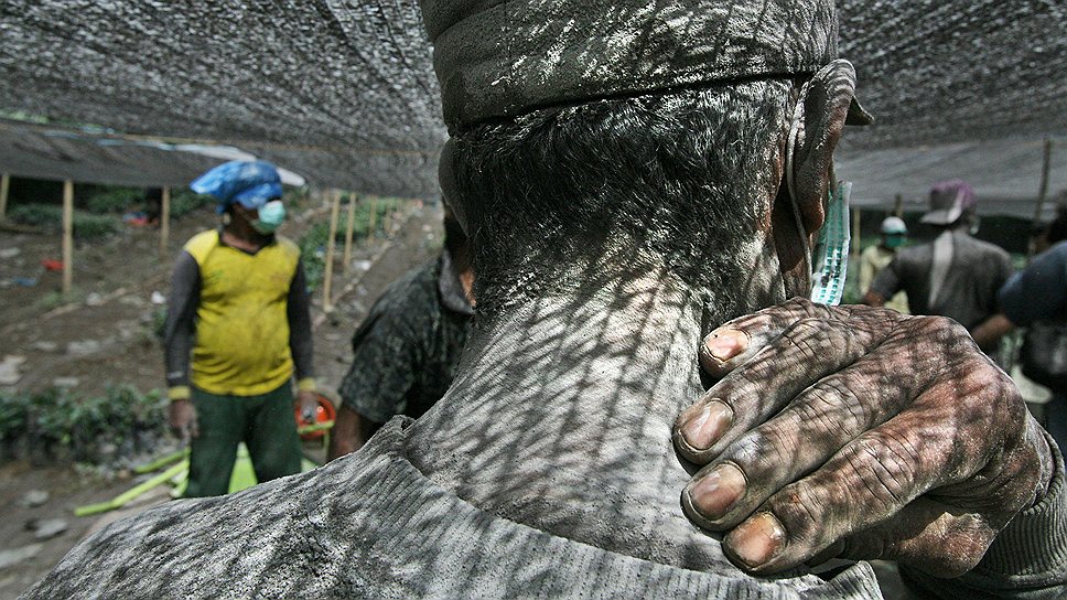 Рабочий, плечи которого покрыты вулканическим пеплом от извержения вулкана Синабун