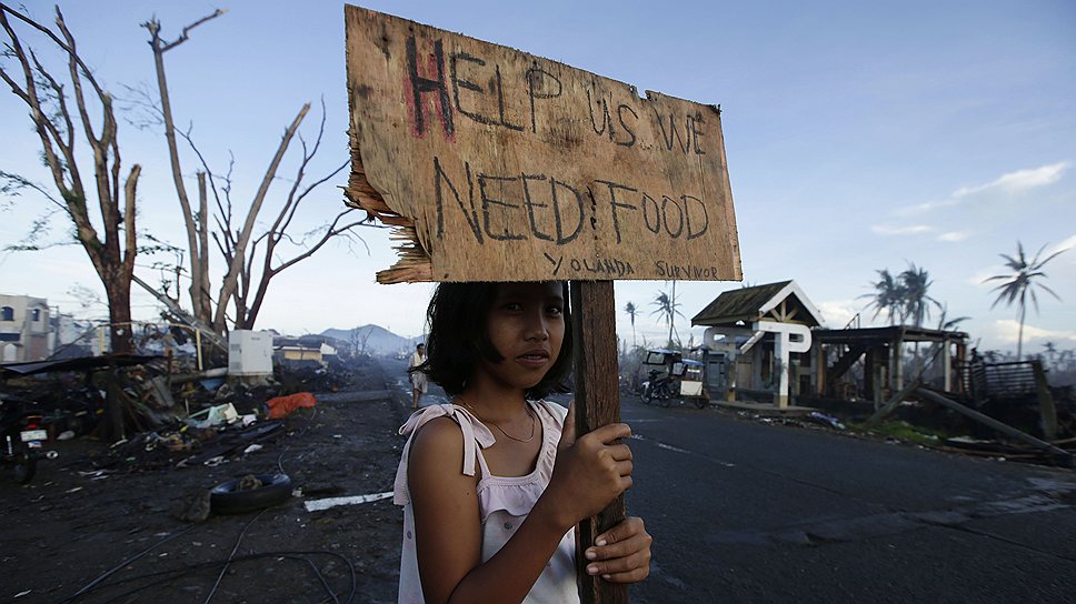 В результате тайфуна, обрушившегося на Филиппины 8 ноября, около 700 тыс. человек остались без крыши над головой. В некоторый городах до сих пор не восстановлены разрушенные стихией дороги, многие люди остаются без продовольствия и необходимых медикаментов
&lt;br>Надпись на табличке в руках девочки: «Помогите! Нам нужна еда»