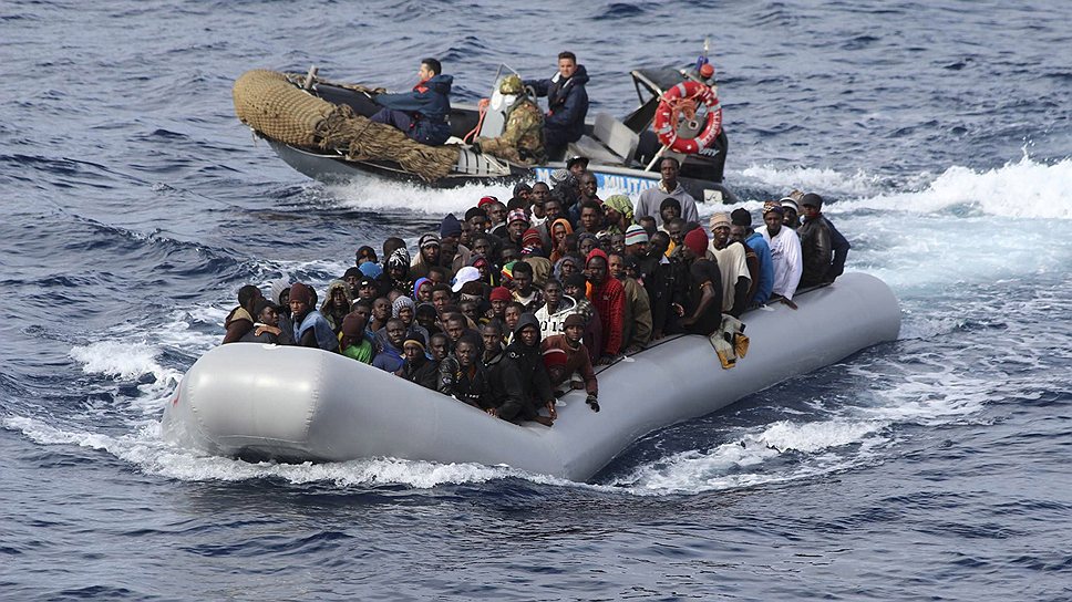 Мигранты сидят в лодке во время спасательной операции итальянского флота у берегов острова Сицилия