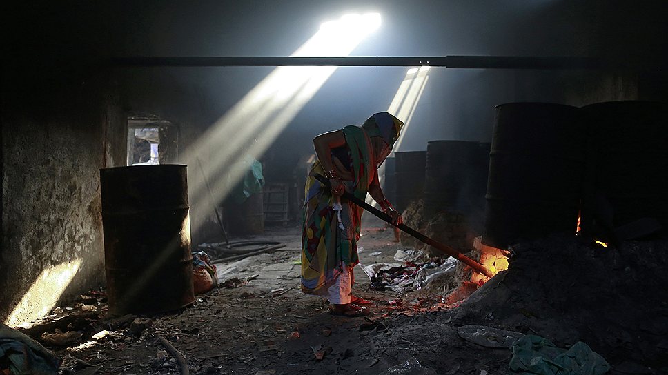 Женщина греет воду для стирки одежды в прачечной в Мумбаи