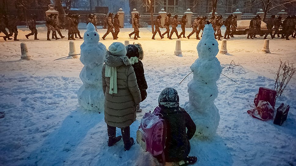 Дети смотрят, как бойцы спецподразделения «Беркут» идут блокировать улицу возле президентской администрации во время протестов в Киеве