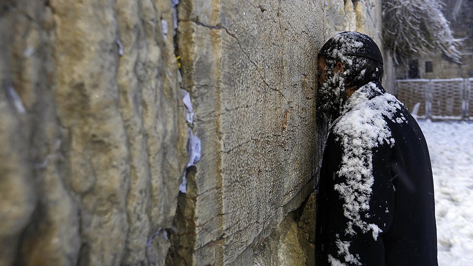 Ортодоксальный еврей молится у Стены плача в Старом Городе Иерусалима во время снегопада