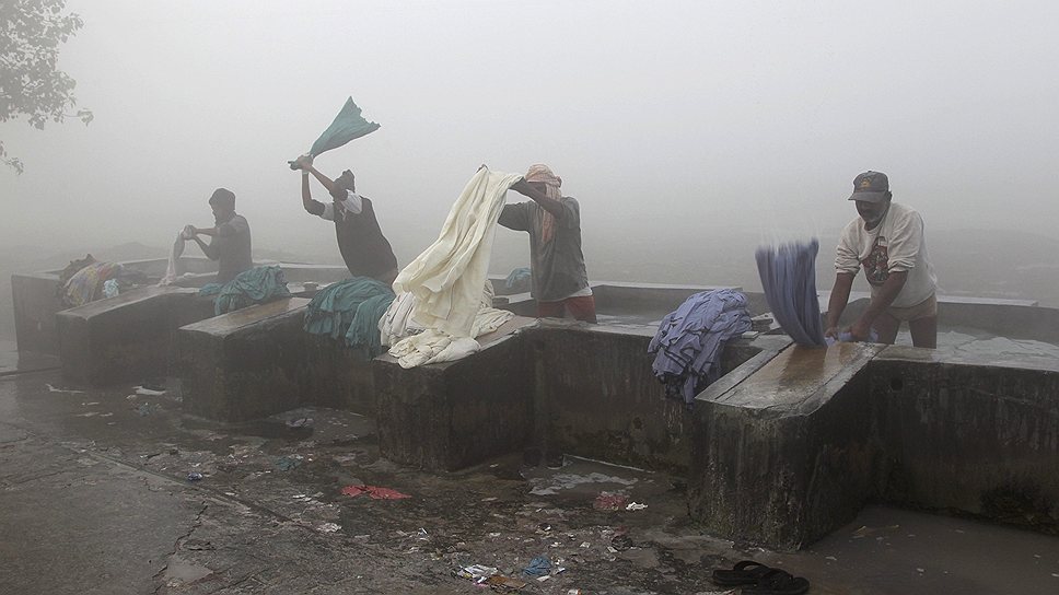 Индийские мужчины-прачки, называемые «дхоби», стирают одежду в открытой прачечной в Аллахабаде