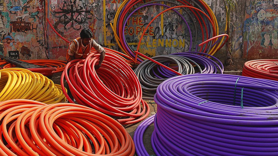 Рабочий среди труб телефонного кабеля на дороге в Мумбаи, Индия 