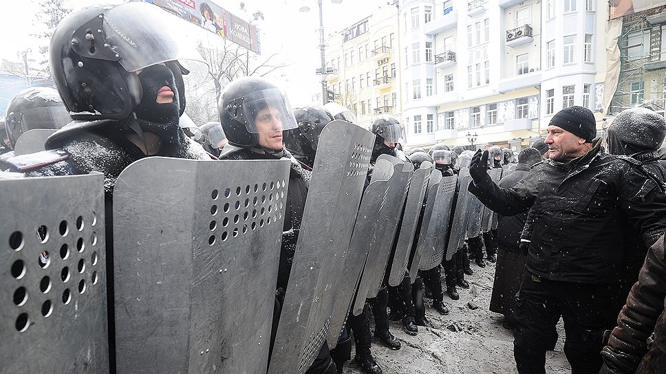 Плотная колонна демонстрантов (300-400 человек), вооруженных палками, с щитами, некоторые с арматурой идут в наступление вдоль улицы Грушевского
