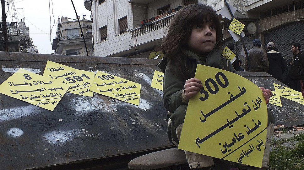 Сирийская девочка с плакатом &quot;300 детей без образования уже два года&quot; во время акции в осажденном районе Хомса, организованной местными активистами для привлечения внимания мирового сообщества к гуманитарным проблемам жителей