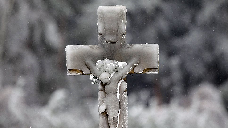 Обледеневший крест у реки в польском городе Алейзув