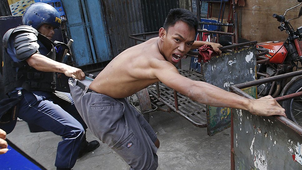 Филиппинский полицейский задерживает сквоттера в Маниле во время сноса незаконно возведенных домов 