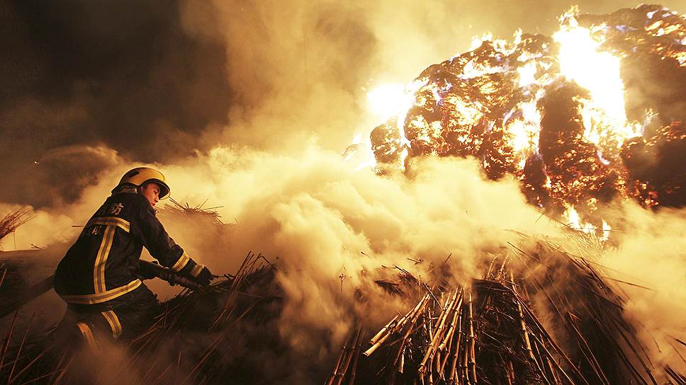 Китайский пожарный тушит тростник на бумажной фабрике в Чандэ, провинция Хунань