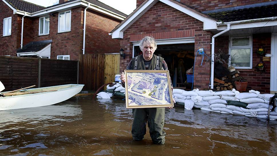 62-летний строитель Дерек Бристоу рядом со своим домом. В его руках картина, которую он успел вынести из затопленного жилища