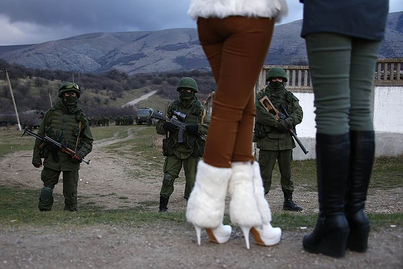 Местные девушки возле украинской военной базы в Перевальном в Крыму, охраняемой солдатами, носящими форму без опознавательных знаков