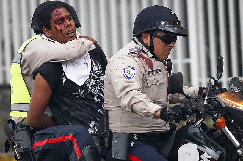 Сотрудники полиции отвозят демонстранта, задержанного в ходе антиправительственных выступлений в Каракасе