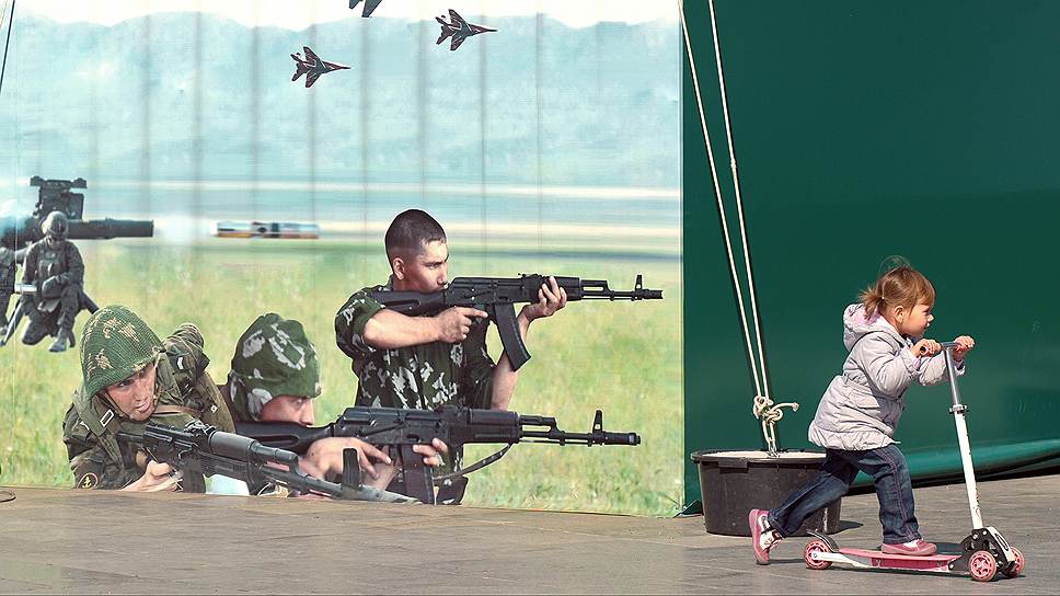 Ребенок на самокате у баннера военной тематики в Ялте