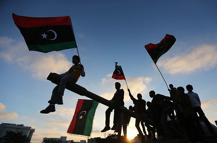 Дети с флагами сидят на танке в Бенгази, во время отмечания третьей годовщины атаки сил, лояльных Муаммару Каддафи
