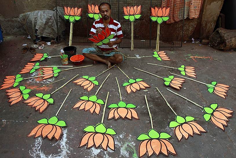 Индийский рабочий раскрашивает вырезанные из картона цветы лотоса в Калькутте. Лотос - предвыборный символ основной оппозиционной партии BJP