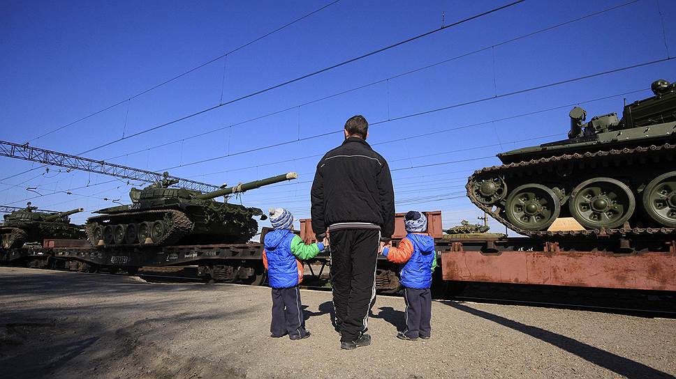 Мужчина с детьми смотрят на российские танки, прибывшие в поселок Гвардейское Симферопольского района