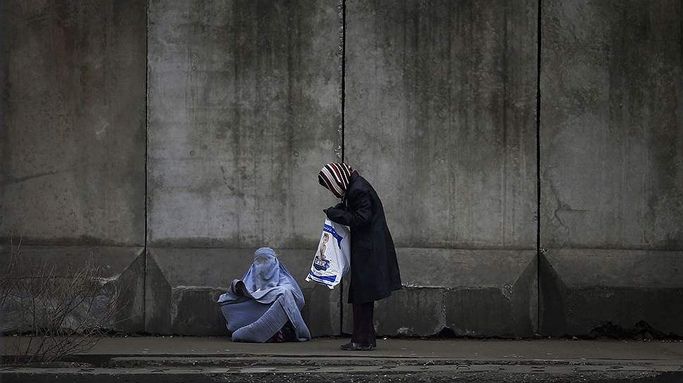 Женщина подает милостыню попрошайке в Кабуле