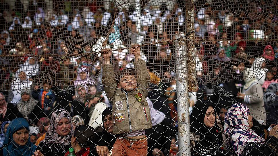 Мальчик лезет на забор, чтобы лучше видеть церемонию принятия новых сотрудников в службу безопасности Палестины в Газе