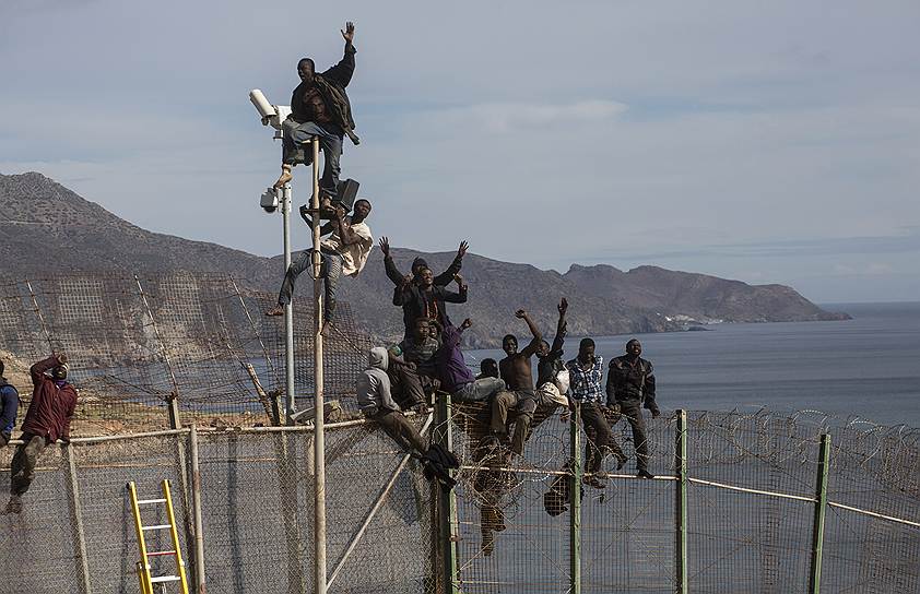 Мигранты на заборе, отделяющем Марокко от испанского анклава Мелилья во время попытки пробраться на территорию Европы