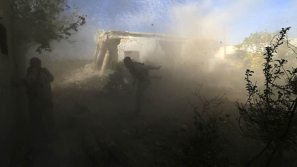 Сирийский повстанец бежит в укрытие во время боя в Идлибе с войсками, лояльными Башару Асаду