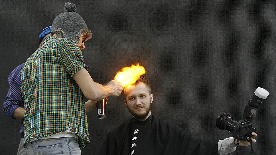 Доброволец делает «селфи», пока его «стригут» с помощью огня на шоу «Барбер трэш» во время фестиваля «Идеал красоты» в Красноярске