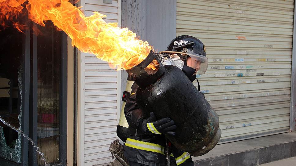 Китайский пожарный выносит газовый баллон из горящего здания в Ухане, провинция Хубэй