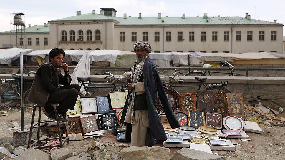 Продавец настенных часов и его клиент на улице в Кабуле