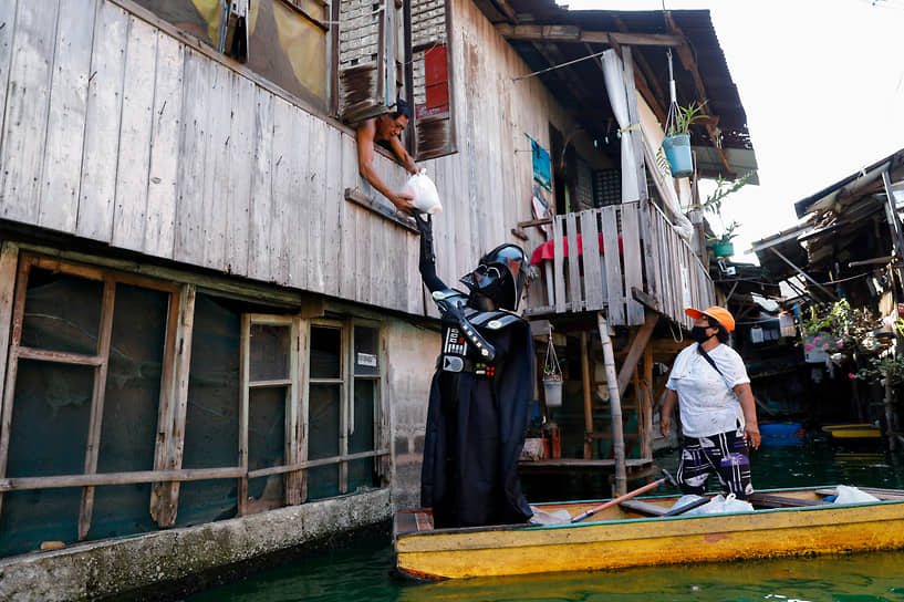 Малабон, Филиппины. Мужчина в костюме Дарта Вейдера передает гуманитарную помощь жителям квартала на воде Artex Compound, 2020 год