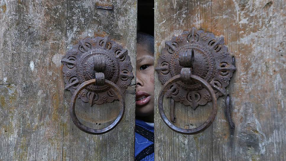 Мальчик выглядывает из ворот своего дома в деревне Лишуй китайской провинции Чжэцзян