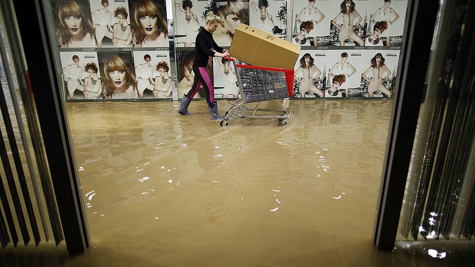 Женщина эвакуирует парикмахерские принадлежности из торгового центра в боснийской Зенице во время наводнения