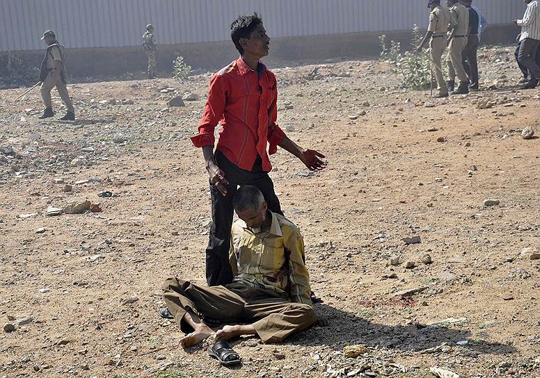 Индиец зовет медиков на помощь своему отцу, раненному во время массовой драки в Хайдарабаде