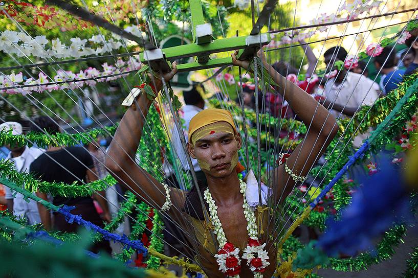 Индус несет на себе конструкцию под названием «кавади», которая держится на теле с помощью металлических спиц, во время празднований в индуистском храме в Янгоне, Мьянма