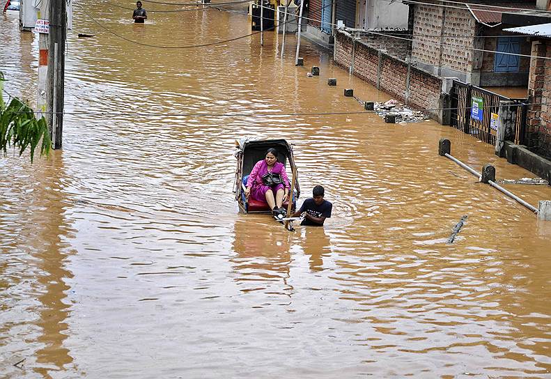 Рикша на затопленной после проливных дождей дороге в Гувахати на северо-востоке Индии
