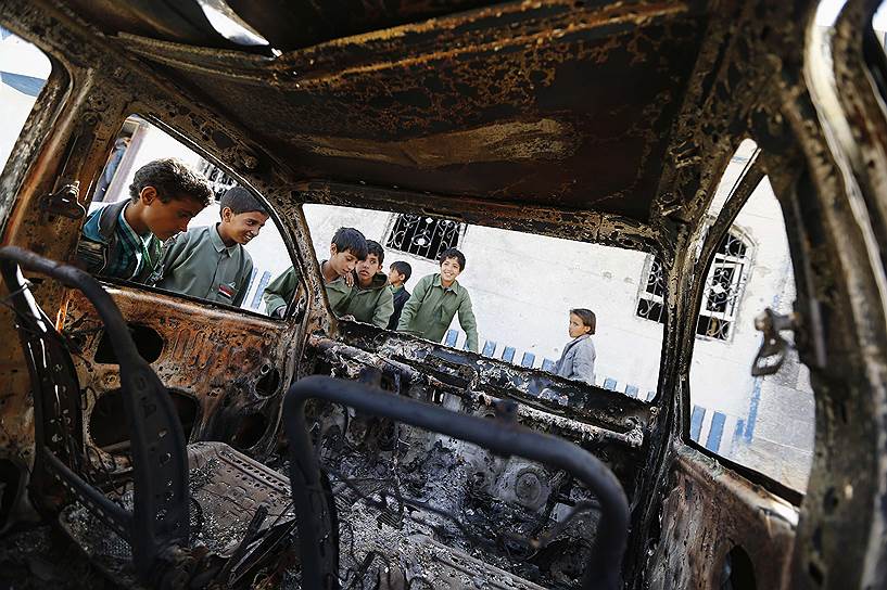 Йеменские дети рассматривают останки автомобиля, сгоревшего во время полицейского рейда против боевиков аль-Каиды в районе Архаб к северу от Саны