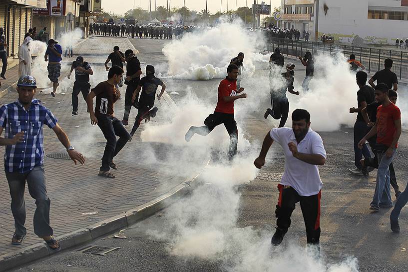 Бахрейнские демонстранты бегут от слезоточивого газа, примененного полицейскими для разгона акции протеста в деревне Ситра к югу от Манамы