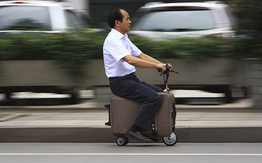 Китайский изобретатель Хэ Лян едет на своем «самодвижущемся чемодане» на улице в Чанше, провинция Хунань. Господин Лян потратил 10 лет на создание этого транспортного средства, развивающего скорость до 20 км/ч. Объема батареи, от которой работает «чемодан», хватает на 50-60 км пути